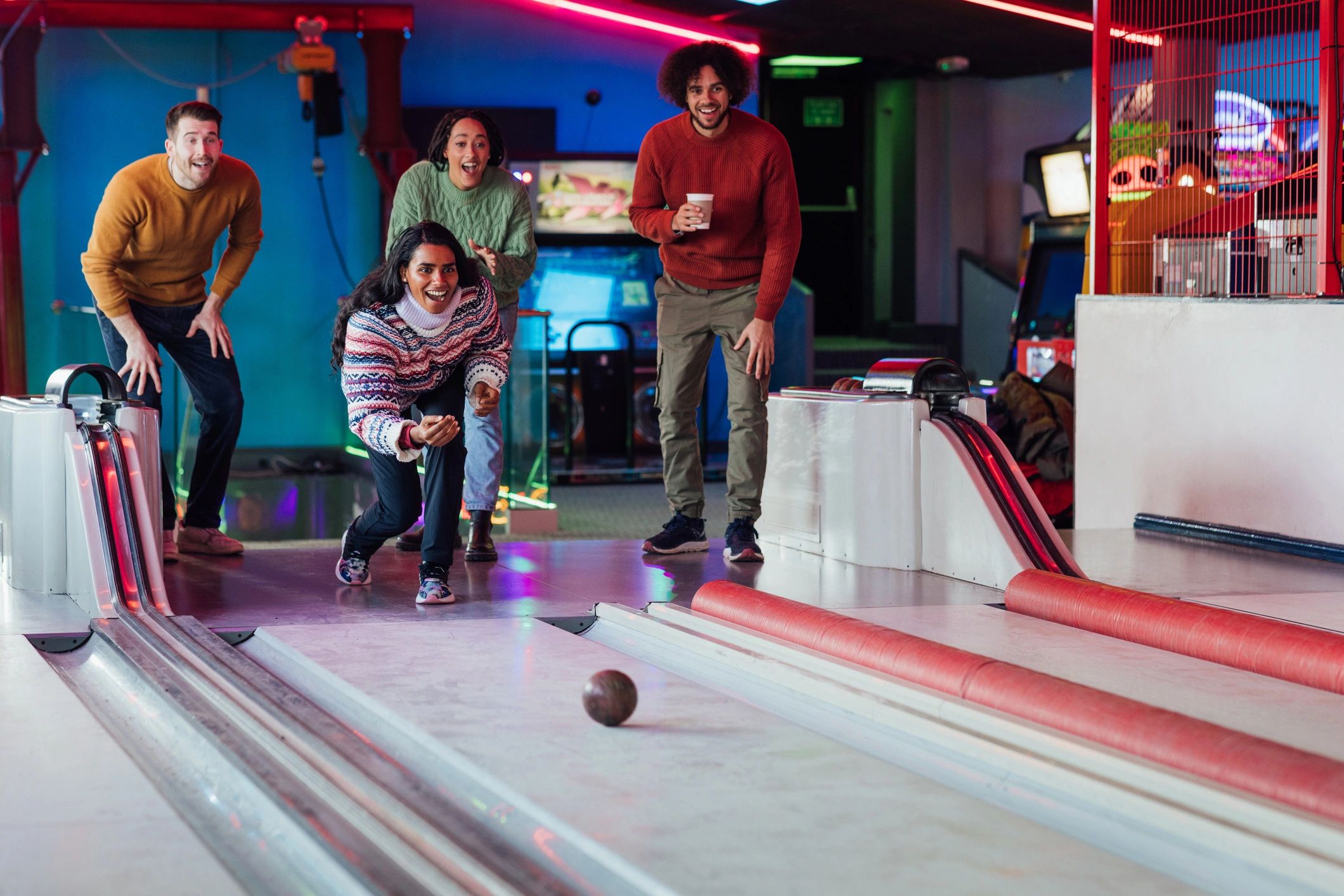 Bowler rolling a ball down the lane with friends watching